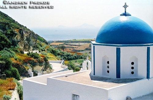 A landscape photo with a blue-domed church on the island of Santorini, Greece