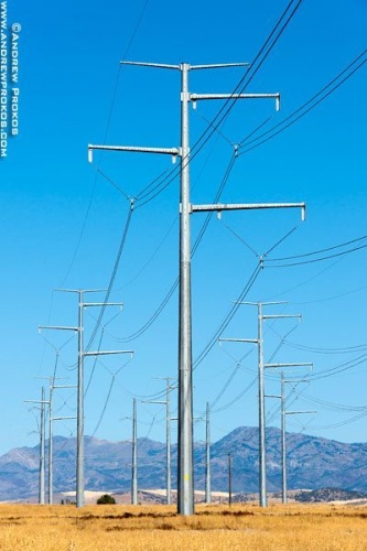 A group of steel electricity transmission towers set in a sparse Southern Idaho landscape