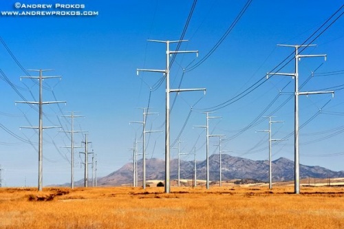 A group of steel electricity transmission towers set in a sparse Southern Idaho landscape