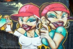 A street mural of girl graffiti artists with spray paint cans, Queens.