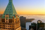 A view of 40 Wall Street, the Financial District, and New York Harbor as seen from an adjacent tower at sunset.