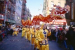 A street scene photo of men in costumes parading a dragon through Chinatown during the Chinese New Year parade, New York City
