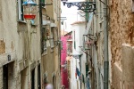 A fine art street scene photo of an alley in the Alfama district of Lisbon, Portugal.