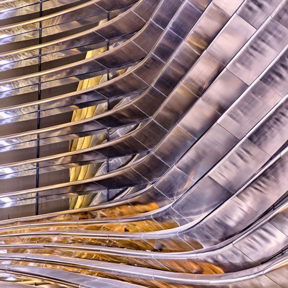 A close-up architectural detail of the curved stainless steel banded facade at the ALIF - Mobility Pavilion at the Dubai World Expo captured at night. Large-scale fine art prints of this fine art architectural photo are available up to 60 inches.