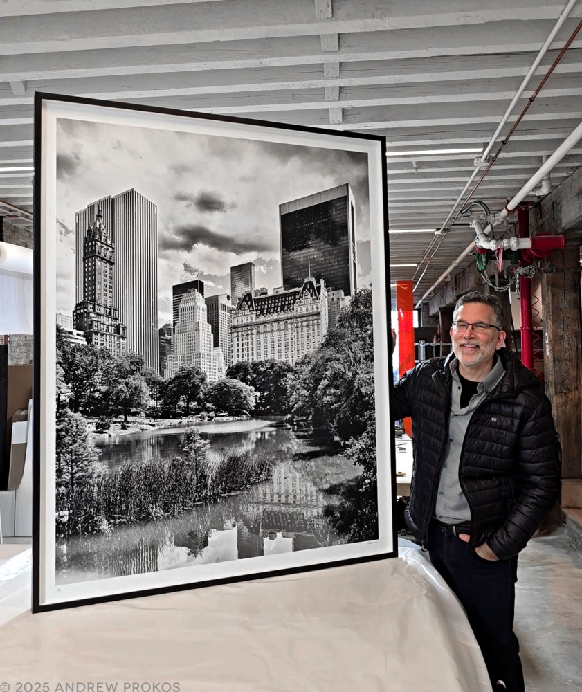Photographer Andrew Prokos with a framed 60x48 inch black and white landscape print of Central Park Pond and the Plaza Hotel