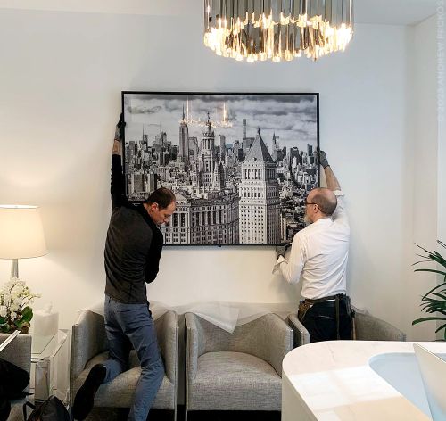 A 60 inch black and white limited edition framed print of 'Municipal Building and Midtown Skyscrapers' by photographer Andrew Prokos being installed in a Park Avenue, New York City medical office