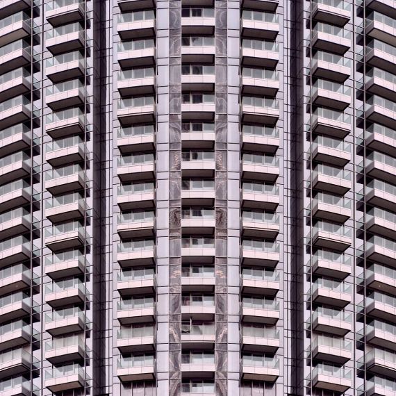 A fine art photograph of a curved contemporary facade with repeating patterns in tones of pink and black. Andrew's Archistracts series is derived fully from lens-based photographic captures. Large-scale limited edition prints of this photo are available up to 72 inches.