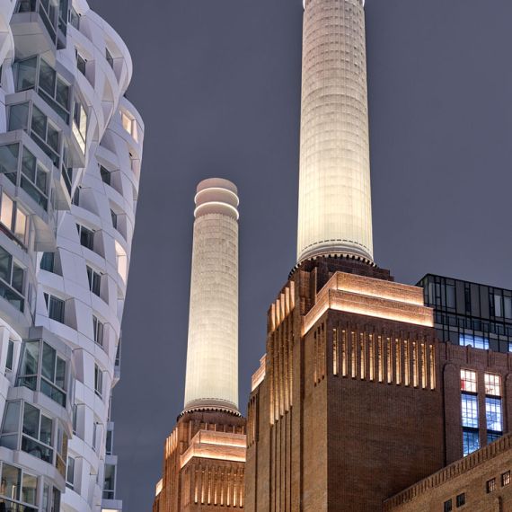 A view of the facade and smokestacks of Battersea Power Station at night, London, United Kingdom. High-definition fine art prints of this photo are available up to 72 inches in height.