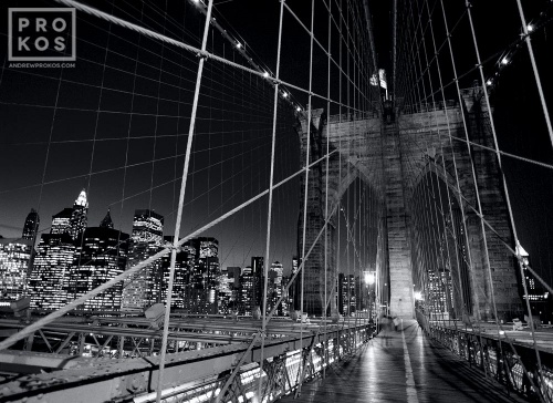 A black and white long-exposure photo of the suspension cables of the Brooklyn Bridge at night, New York City