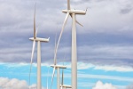 A landscape photo of massive wind turbines dwarfing an abandoned farmhouse at Biglow Canyon wind farm in Oregon