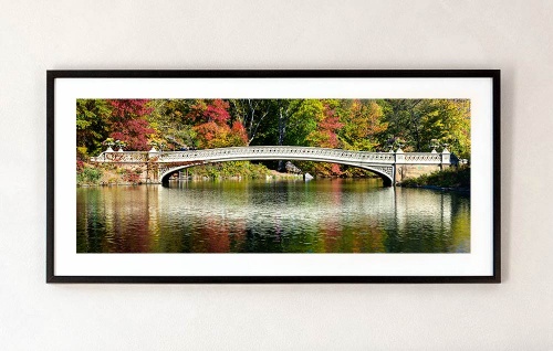 A framed fine art print of "Panoramic View of Bow Bridge in Autumn, Central Park” by photographer Andrew Prokos.