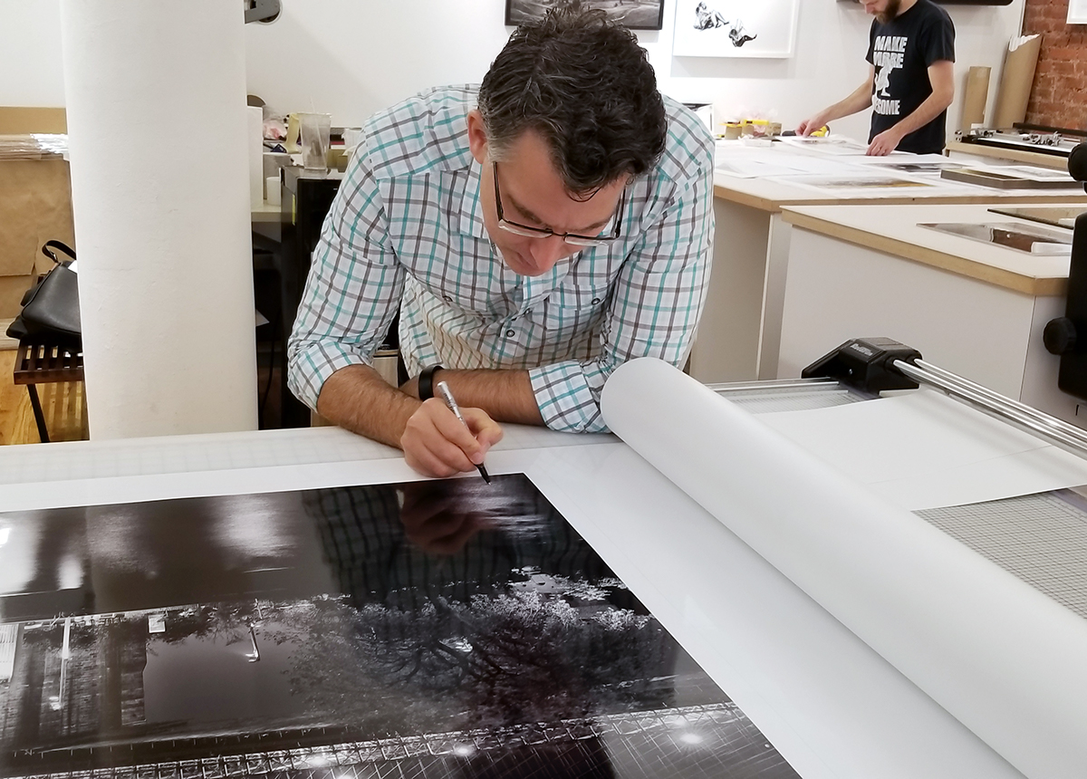 Andrew Prokos signing a 90" limited edition print of "Panoramic Skyline of Brooklyn Bridge and Lower Manhattan at Night"