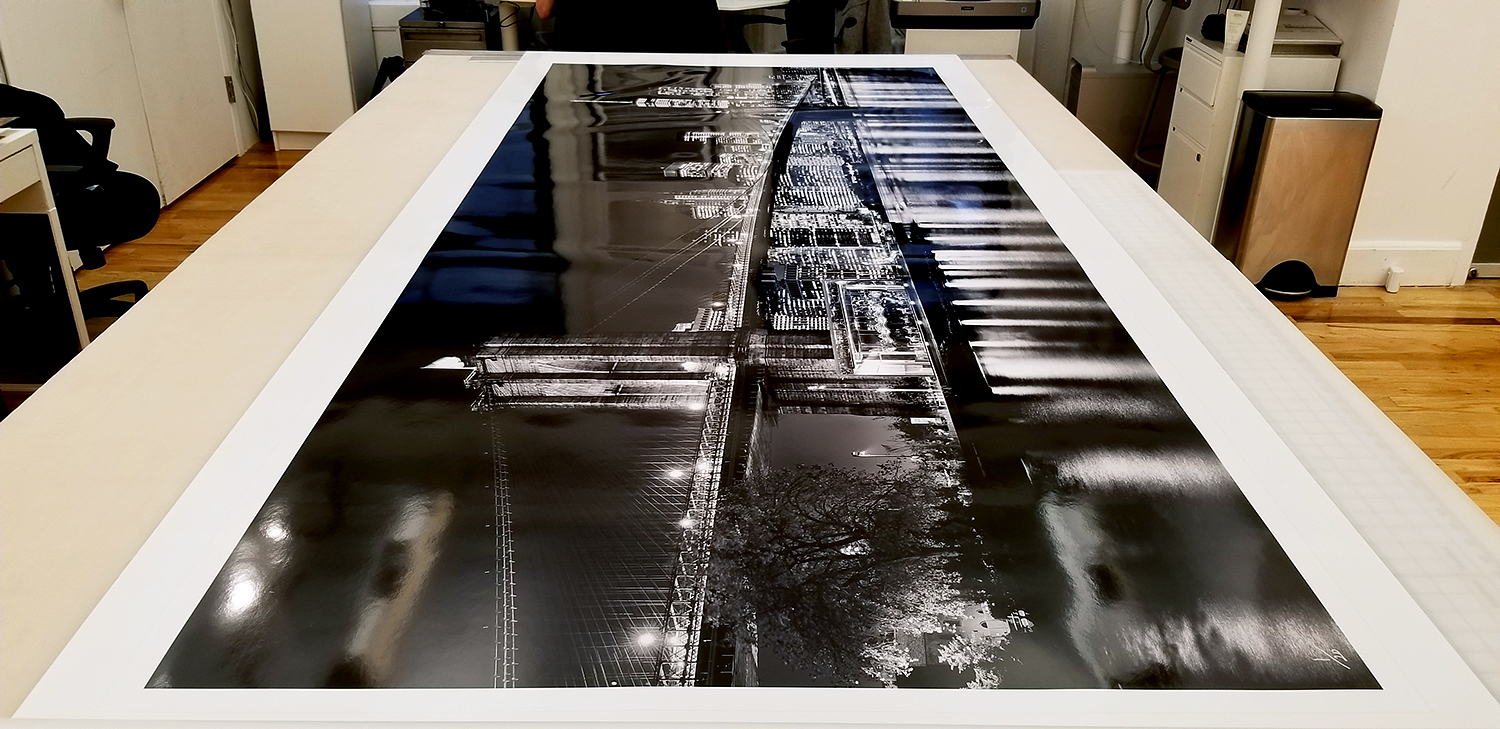A 90 inch limited edition print of "Panoramic Skyline of Brooklyn Bridge and Lower Manhattan at Night" by photographer Andrew Prokos