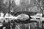 A black and white panoramic view of Gapstow Bridge and the Lake in Central Park in Winter