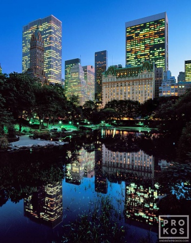 A high-definition fine art photo of the skyscrapers along Fifth Avenue, the Plaza Hotel, and the Pond in Central Park at dusk