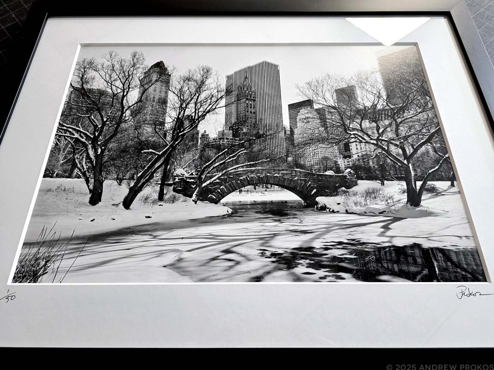 A framed black and white landscape photo of Central Park and the Gapstow Bridge under a blanket of snow by photographer Andrew Prokos