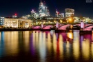 A high-definition photograph of the City of London skyline, the Southwark Bridge, and the golden lights of London reflected on the Thames River at night. Large-format fine art prints of this photo are available up to 80 inches in width and framed in various wood, metal, and acrylic styles. 