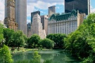 A color landscape photo of the Plaza Hotel and Fifth Avenue skyline as seen from the Pond in Central Park, New York City