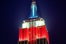 An architectural photo of the Empire State Building at night, with lights in red, white, and blue, New York City