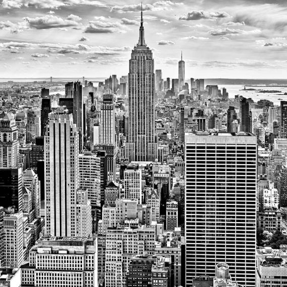A black and white cityscape of the skyscrapers of Midtown Manhattan NYC and the Empire State Building as seen from from Rockefeller Center by photographer Andrew Prokos