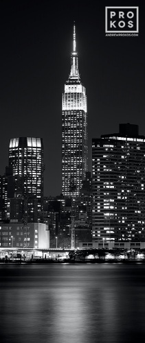 A vertical long-exposure cityscape photo of the Empire State Building at night in black and white, New York City