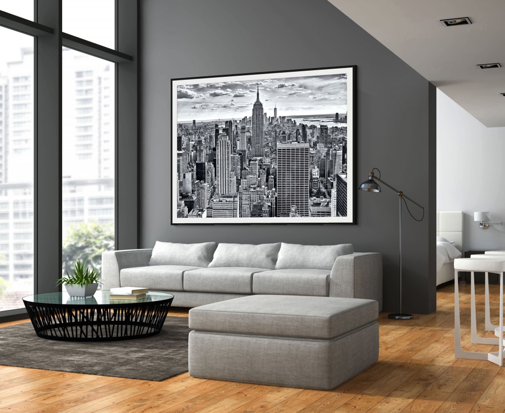 A large-scale black and white framed cityscape print of the Empire State Building and Midtown Manhattan by photographer Andrew Prokos, seen in a luxury home.