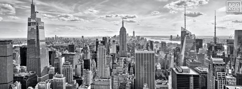 A black and white panoramic skyline of the skyscrapers of Midtown Manhattan NYC and the Empire State Building as seen from from Rockefeller Center by photographer Andrew Prokos