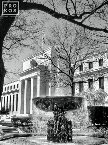 Black and white photography of the United States Federal Reserve building in Washington DC, with a flowing fountain in the foreground. Fine art prints of this photo are available framed in contemporary styles. 