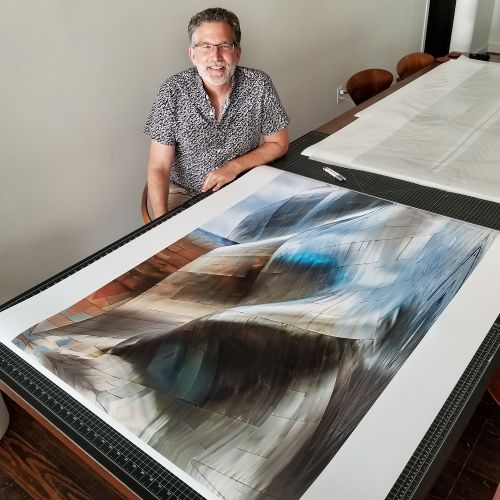 Photographer Andrew Prokos seen with a large-scale fine art print from his architectural series 'Gehry's Children'