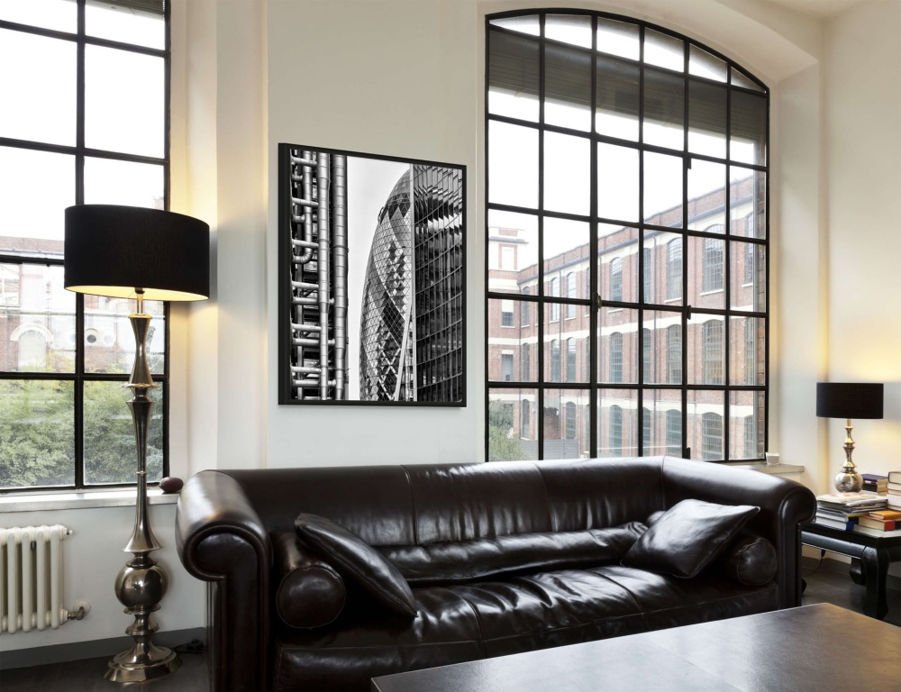 A black and white framed photograph of the 30 St. Mary Axe (the Gherkin), the Lloyd's Building in London seen in a luxury loft interior. High-definition fine art prints of this photo are available up to 72 inches in height.