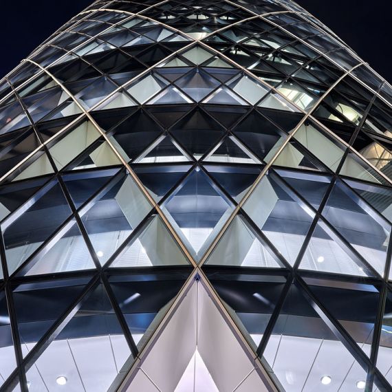 A striking close-up architectural view of 30 St. Mary Axe (aka the Gherkin) building at night, London, United Kingdom
