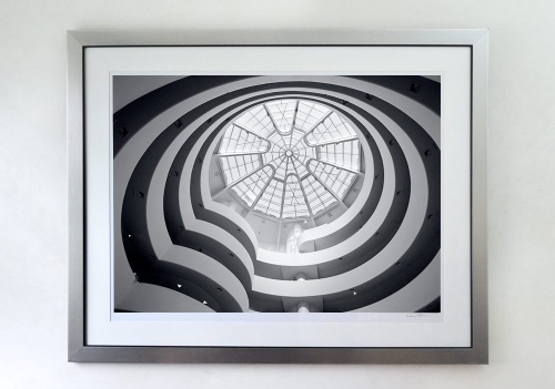 A 30x40 inch black and white photo of the Guggenheim Museum interior framed with a brushed silver wood frame