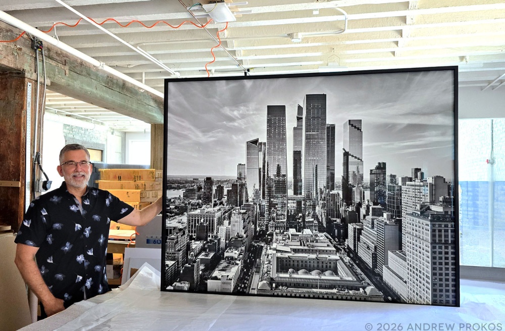 Photographer Andrew Prokos, seen with a 55x72 inch framed photo of "Hudson Yards and Manhattan West Cityscape" in black and white.