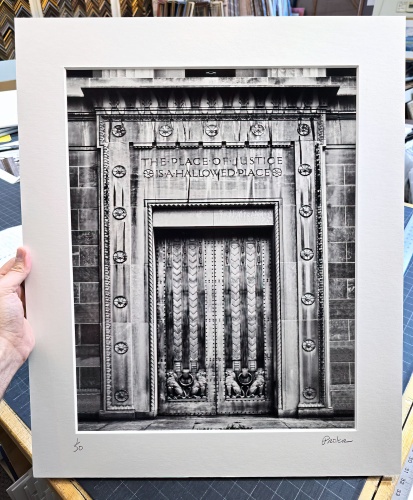 A black and white matted and framed architectural print of the Art Deco doors of the U.S. Justice Department in Washington DC by photographer Andrew Prokos