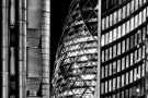 A black and white view of 30 St. Mary Axe (aka the Gherkin), the Lloyd's building, and Willis Towers in the City of London at night
