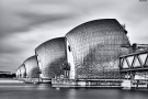 A four minute long-exposure black and white photograph of the Thames Barrier in London, United Kingdom.