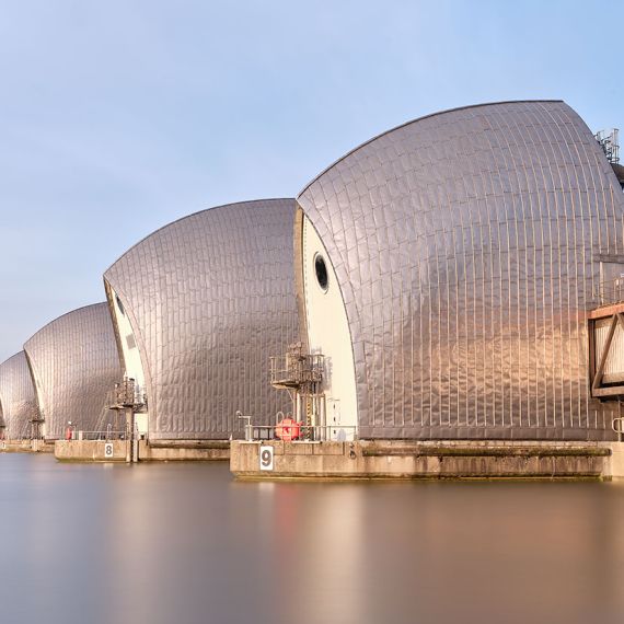 Long-exposure fine art photography of the Thames Barrier in London, United Kingdom. Captured with an eight-minute exposure time, the flowing river and sky are rendered with a soft ethereal quality. Large-format fine art prints of this photo are available up to 72 inches in width.