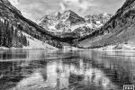 A black and white landscape photo of the Maroon Bells mountain range and an icy Maroon Lake, Aspen, Colorado. Fine art prints of this photo are available framed in various wood, metal and acrylic styles. 