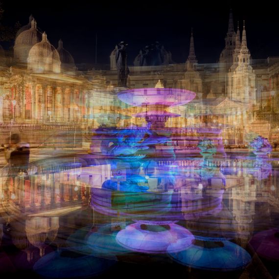 A multiple-exposure view of the fountains of Trafalgar Square, London at night from Andrew's photography series 'Multiplicity'. The pool reflects buildings on the square, including the National Portrait Gallery, and a pair of lovers is captured sitting at the edge of the pool in an embrace.