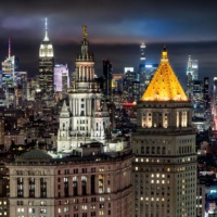 A fine art photograph of the Municipal Building, 40 Centre Street, and the skyscrapers of Midtown Manhattan and the Empire State Building at night in the distance, New York City