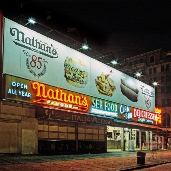 A street scene photo of Nathan's Famous restaurant at night in Coney Island, Brooklyn