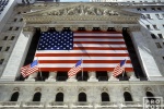 An architectural exterior photo of the New York Stock Exchange (NYSE) draped with American flags. Fine art prints of this photo are available framed in various styles. 