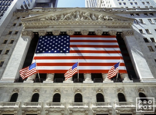 An architectural exterior photo of the New York Stock Exchange (NYSE) draped with American flags. Fine art prints of this photo are available framed in various styles. 
