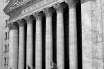 A black and white architectural view of the New York Stock Exchange (NYSE) during the day as seen from Wall Street by fine art photographer Andrew Prokos. Fine art photography prints of this photo are available framed in various wood, metal, and acrylic styles.