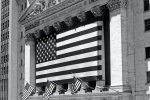 A black and white fine art photo of the New York Stock Exchange exterior with American flags