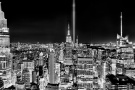 A black and white panoramic cityscape capturing a wide angle view of Midtown Manhattan, the Empire State Building, and the Tribute in Light as seen from Rockefeller Center at night, New York City. Also shown are the Chrysler Building, One Vanderbilt and the Bank of America building. Captured on the 20th Anniversary of September 11th on 9/11/2021. Large-format fine art prints of this photo are available up to 120 inches in width.