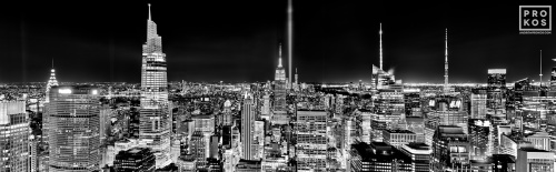 A black and white panoramic cityscape capturing a wide angle view of Midtown Manhattan, the Empire State Building, and the Tribute in Light as seen from Rockefeller Center at night, New York City. Also shown are the Chrysler Building, One Vanderbilt and the Bank of America building. Captured on the 20th Anniversary of September 11th on 9/11/2021. Large-format fine art prints of this photo are available up to 120 inches in width.