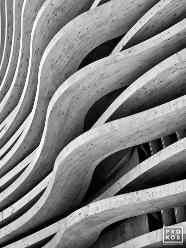 Black and white photography of a curved architectural facade made of cedarwood beams. Large-scale fine art prints of this photo are available up to 80 inches and framed in contemporary wood, metal and acrylic styles. 