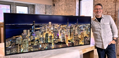 Photographer Andrew Prokos with a 65 inch framed fine art photo of Panoramic Cityscape of Chicago at Night. The photo has been mounted with matte acrylic and set inside a solid wood floater frame.