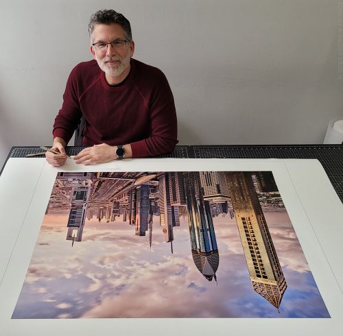Photographer Andrew Prokos signing a large-format limited edition photograph of the Dubai Cityscape for a photography exhibition.